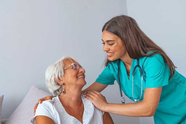 A resident and family member speaking with a staff member in a warmly lit assisted living common area.